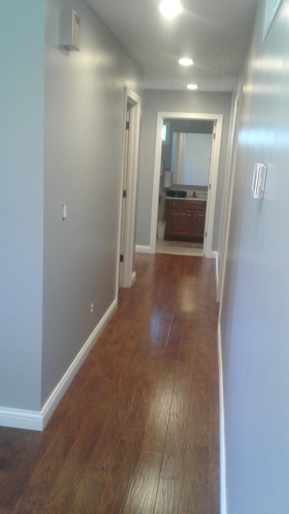 Hallway with gray walls, white trim and wood flooring