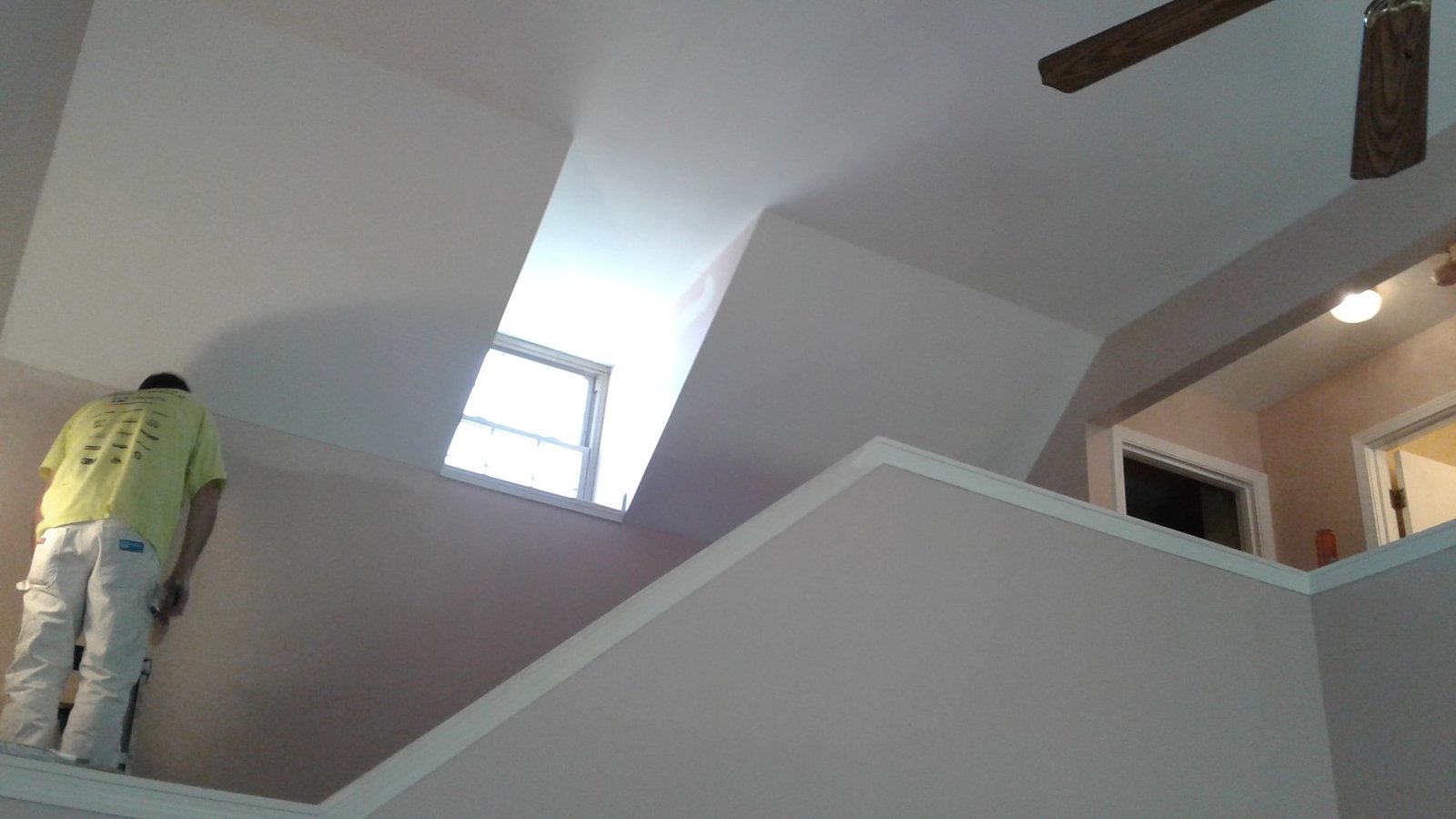 Painter working on an upper wall in a vaulted living space