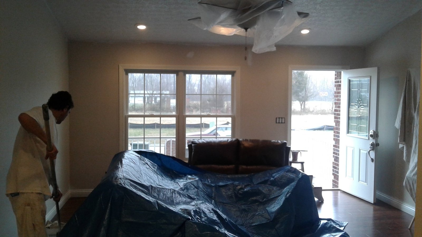 Painter working beside protected furniture in a living room
