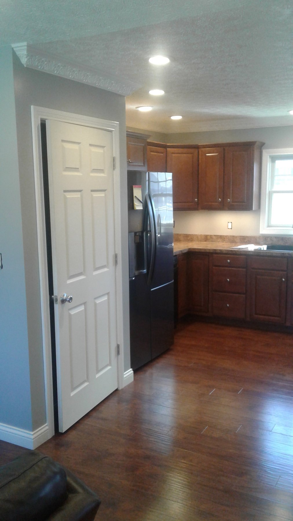 Kitchen interior with gray walls, white trim, wood flooring and wood cabinets