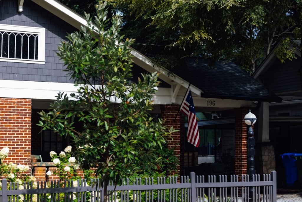 Illustrative house exterior with a porch, fence and tree