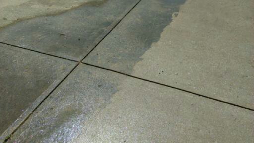 Concrete walkway with cleaned and uncleaned sections during washing